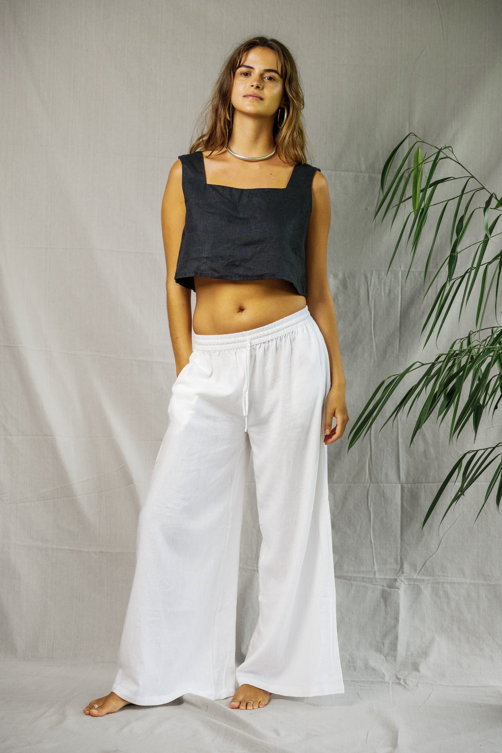 White wide-leg linen pants with elastic waistband styled with a black cropped square-neck top.
