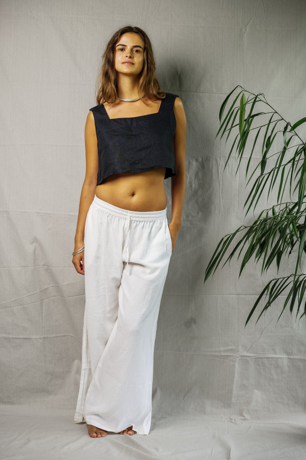 Black sleeveless linen crop top with square neckline paired with loose white linen wide-leg pants.