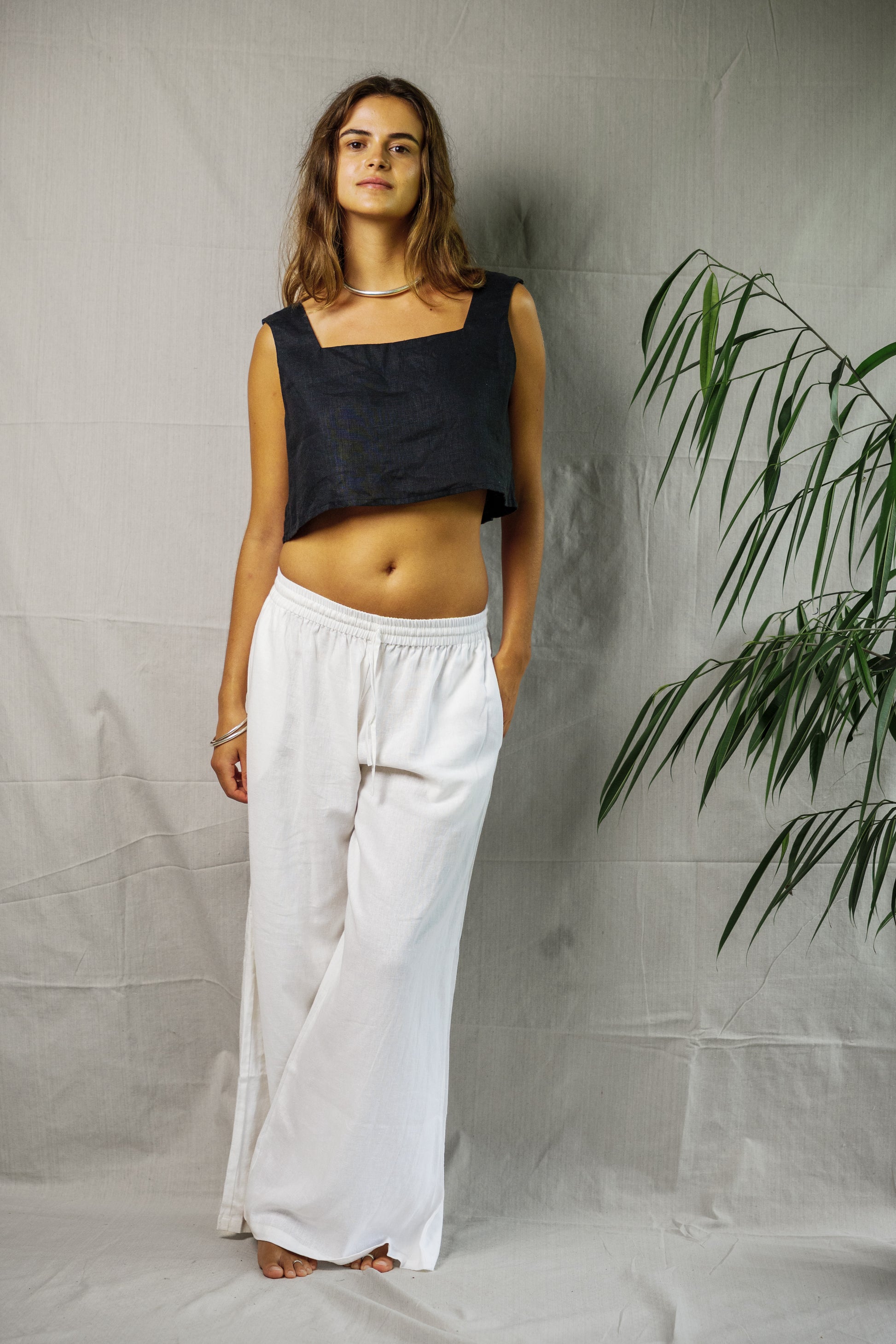 Black sleeveless linen crop top with square neckline paired with loose white linen wide-leg pants.