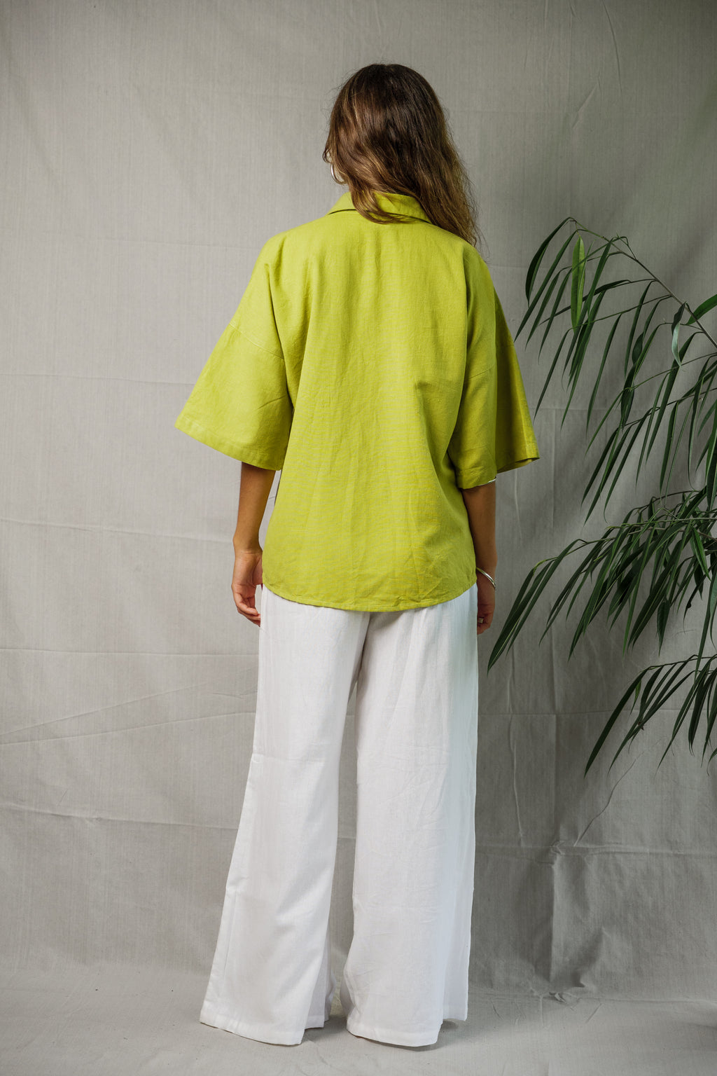 Linen shirt in pistachio green with short sleeves and relaxed fit shown from back.