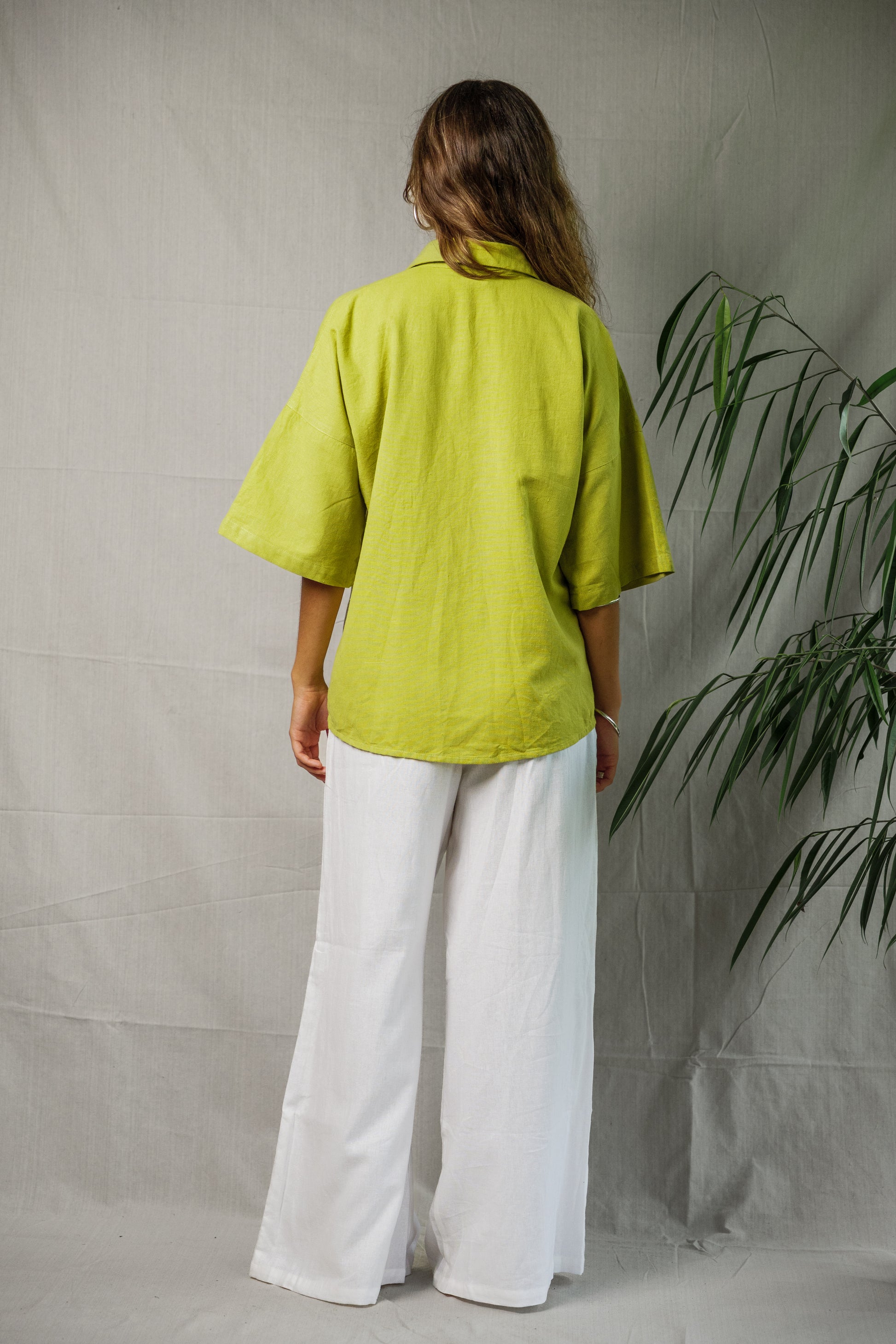 Linen shirt in pistachio green with short sleeves and relaxed fit shown from back.