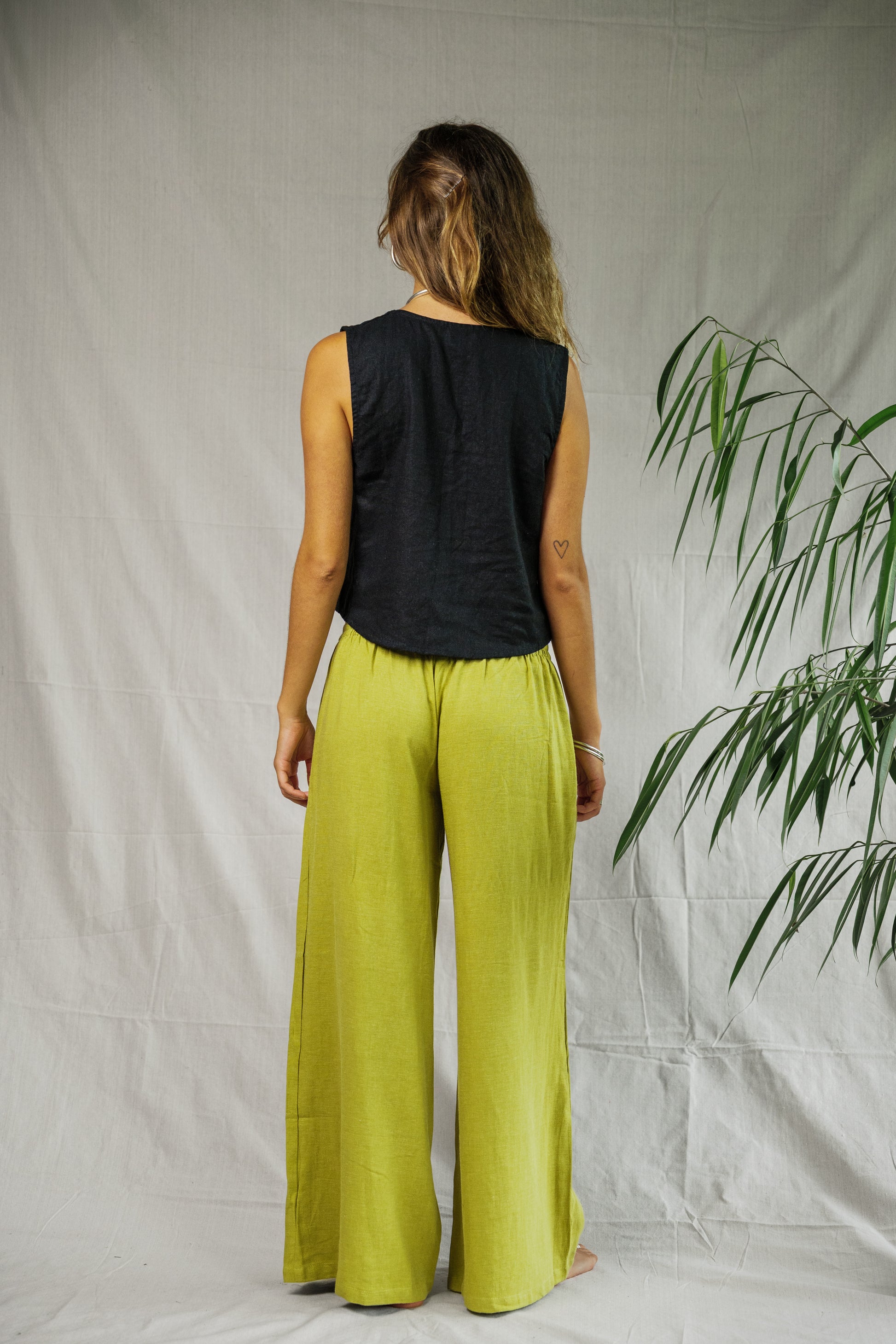 Black sleeveless linen vest with a relaxed fit worn with wide-leg pistachio linen pants.