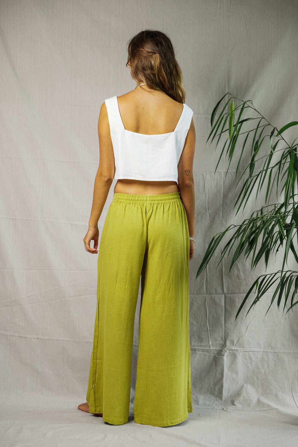 Lime green wide-leg linen pants with elastic waist worn with white sleeveless crop top.
