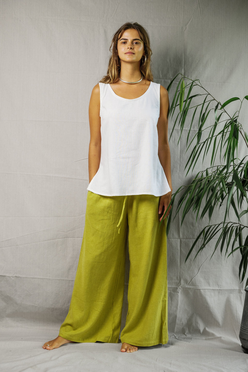 White sleeveless linen singlet with scoop neckline and relaxed fit worn with loose lime green pants.