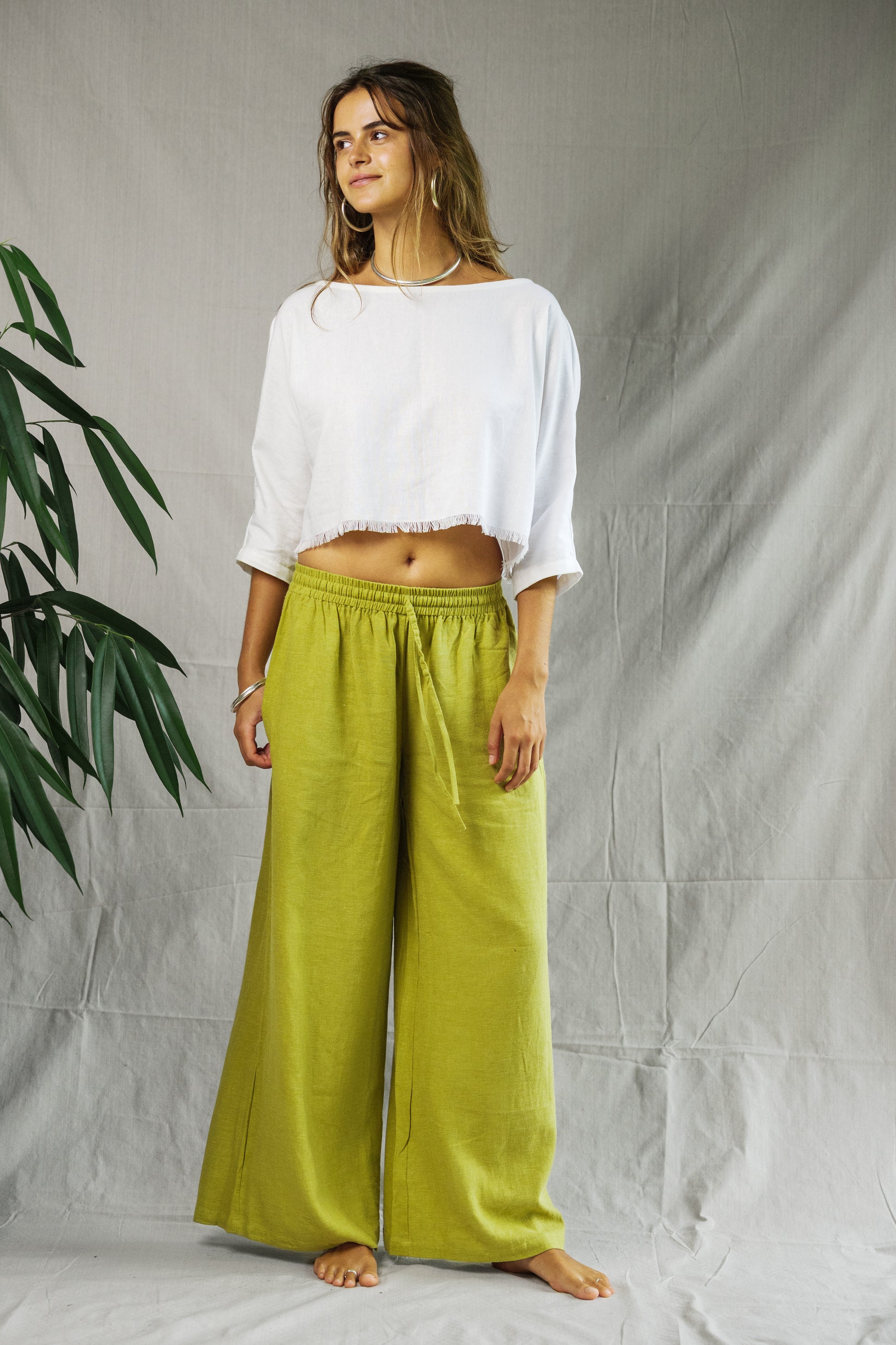 White cropped linen tee with loose fit and 3/4 sleeves worn with olive green wide-leg pants.
