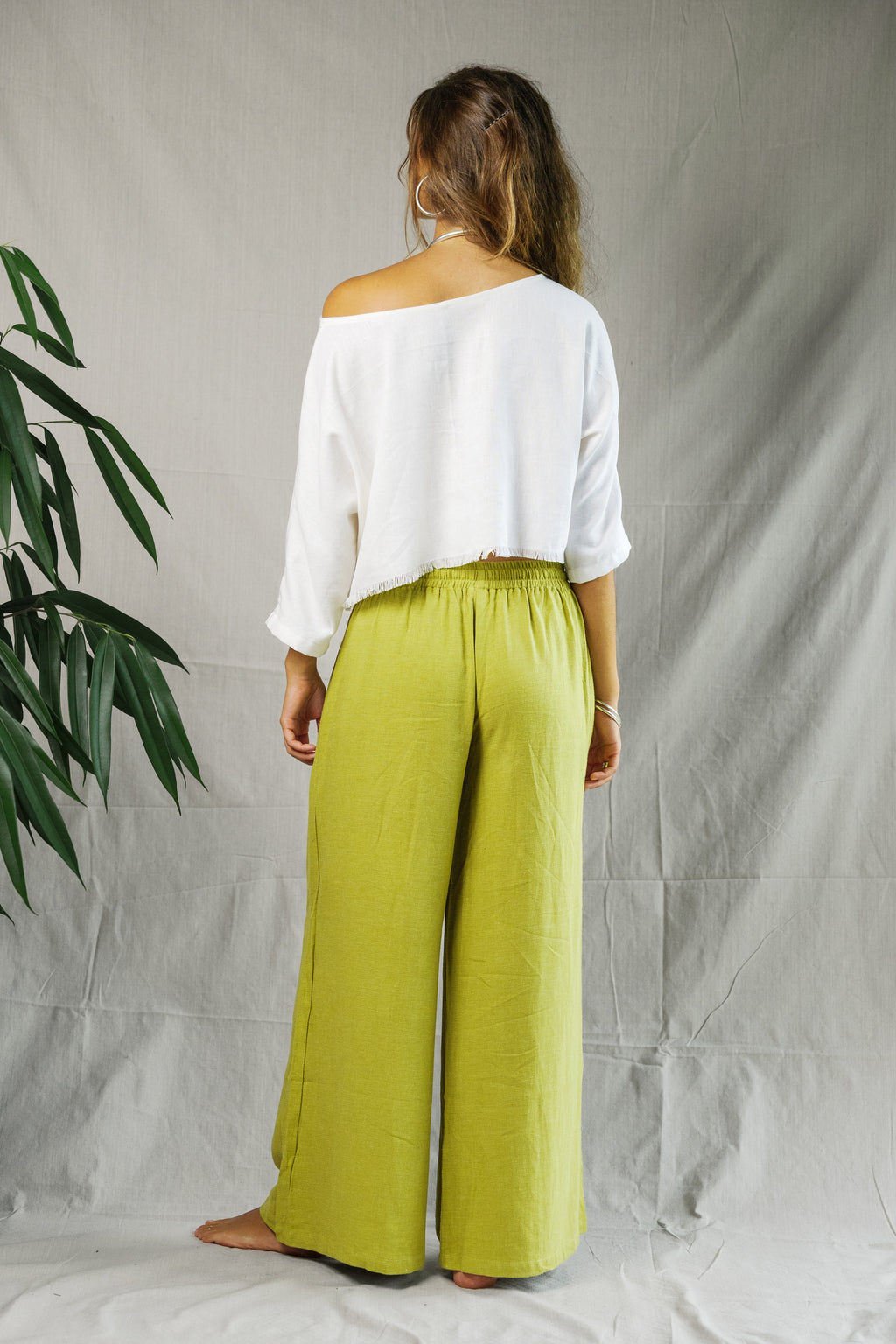 White cropped linen tee with three-quarter sleeves paired with loose lime green wide-leg pants.