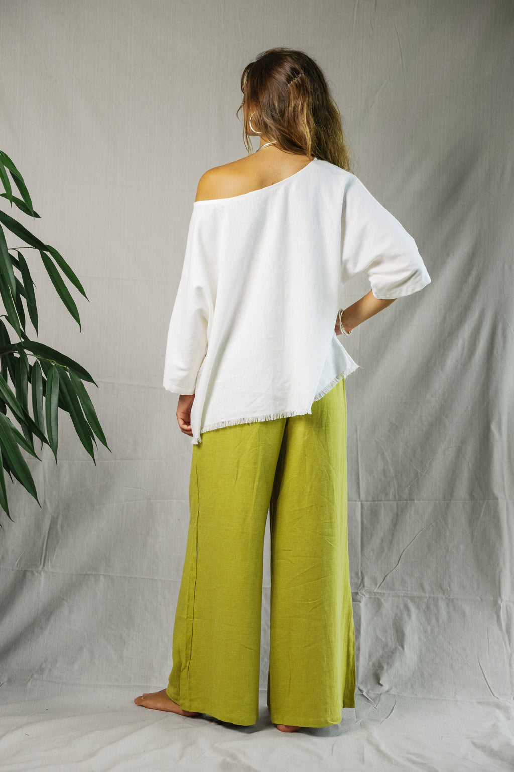 Woman wearing loose white off-shoulder linen tee paired with wide-leg lime green linen pants.