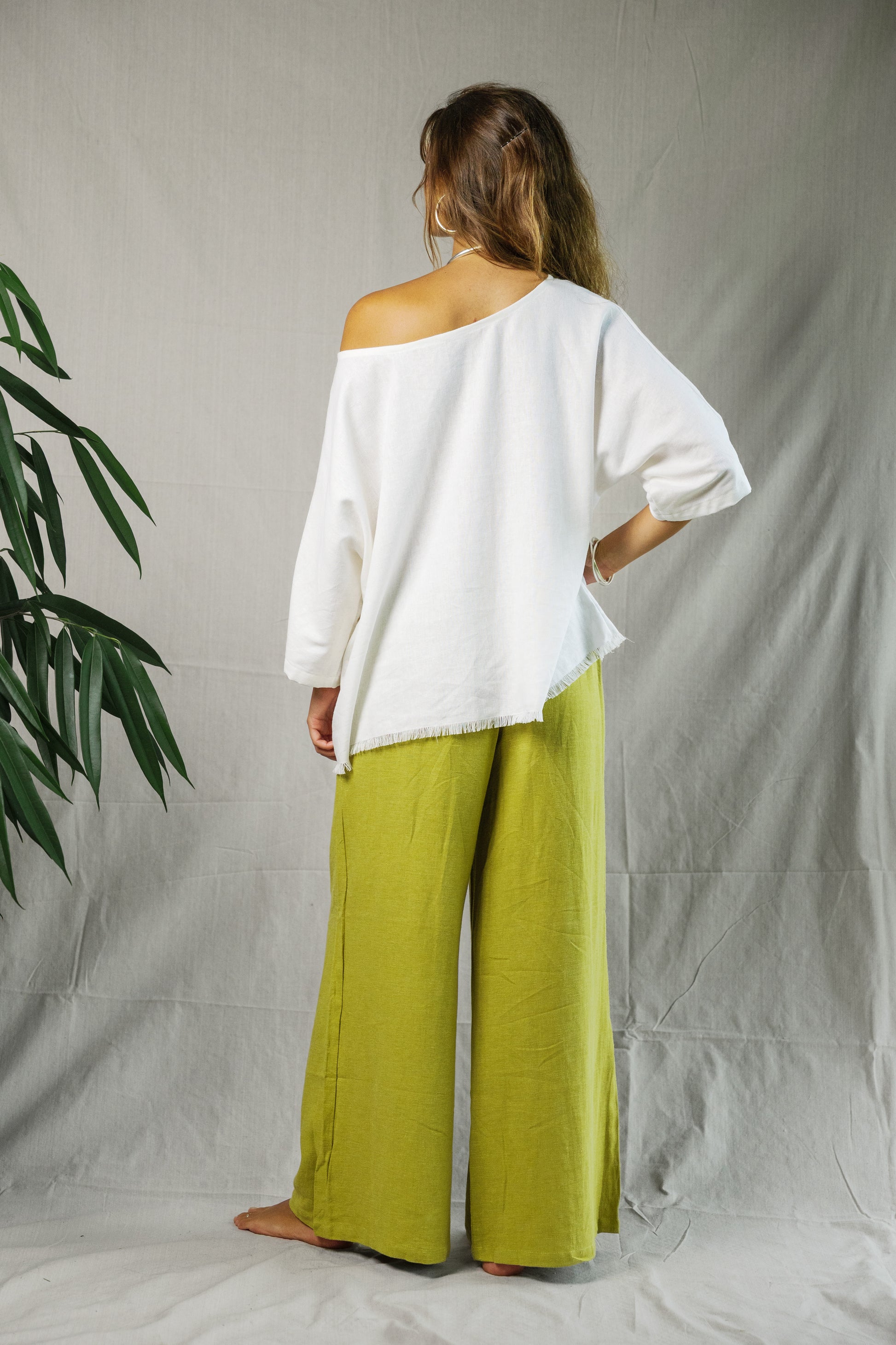 Woman wearing loose white off-shoulder linen tee paired with wide-leg lime green linen pants.