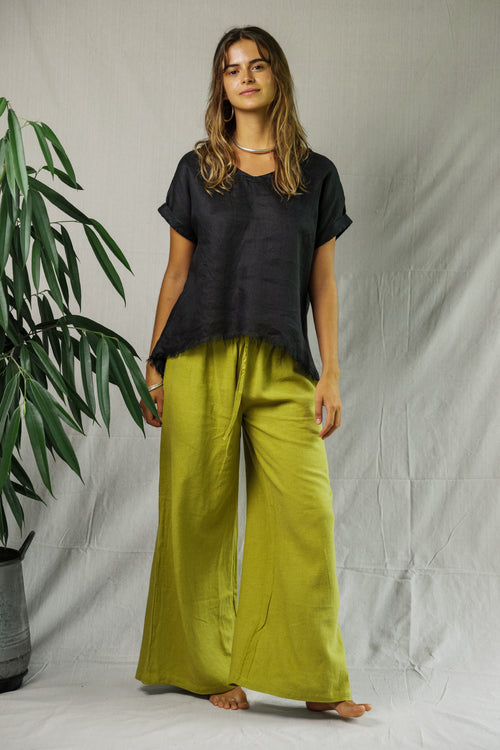 Black short-sleeve linen tee with relaxed fit on model paired with wide-leg yellow pants.