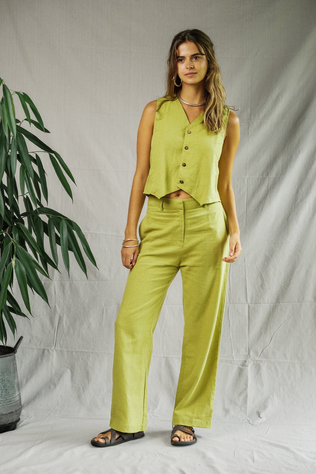 Sleeveless pistachio linen vest with buttons, paired with matching wide-leg pants and sandals.