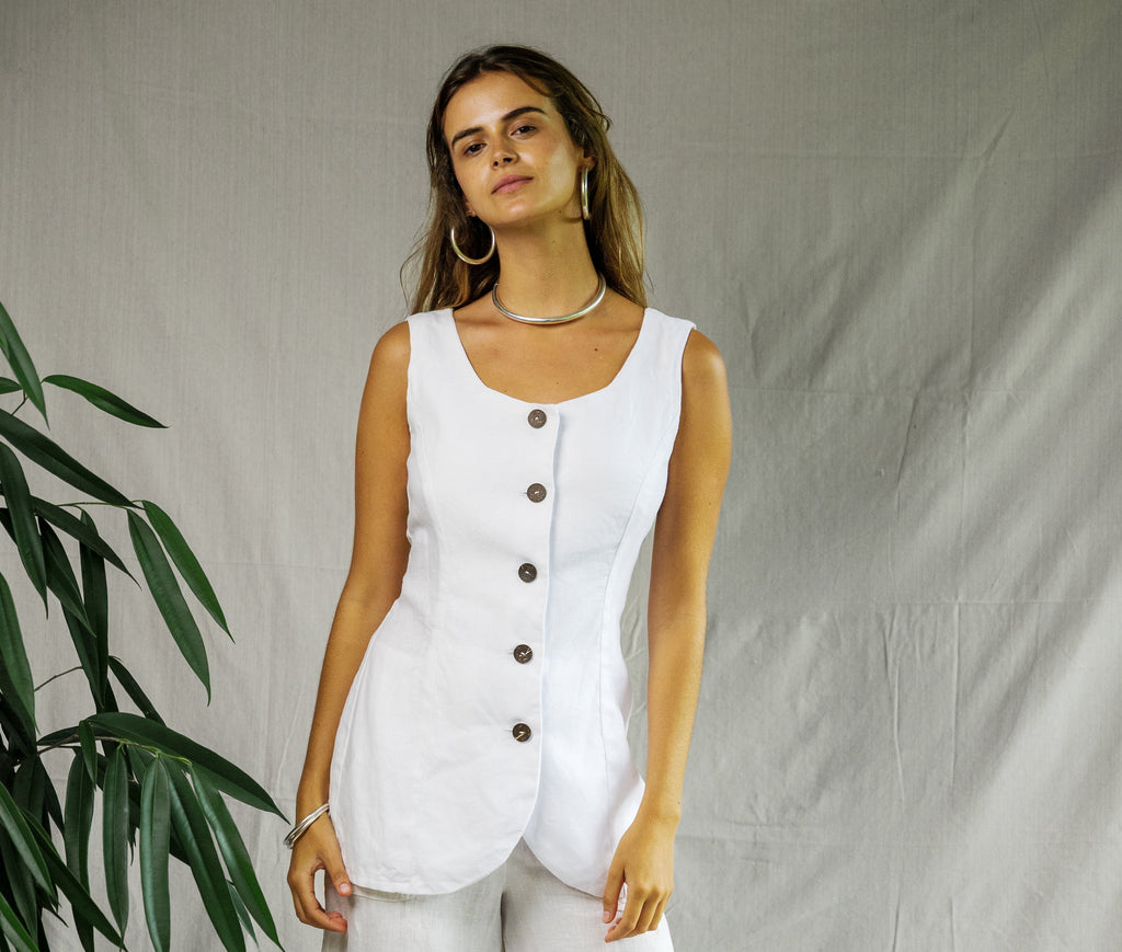 White sleeveless linen sailor vest with front buttons and scoop neckline worn with matching wide-leg pants.