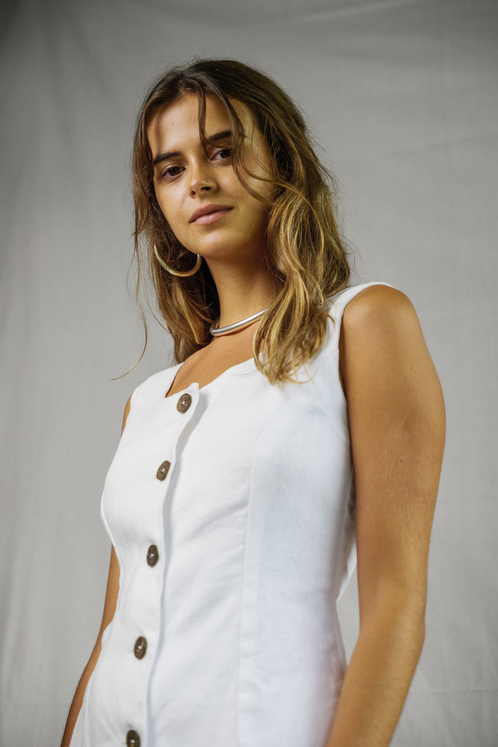 White sleeveless linen vest with front buttons and square neckline, breathable fabric.
