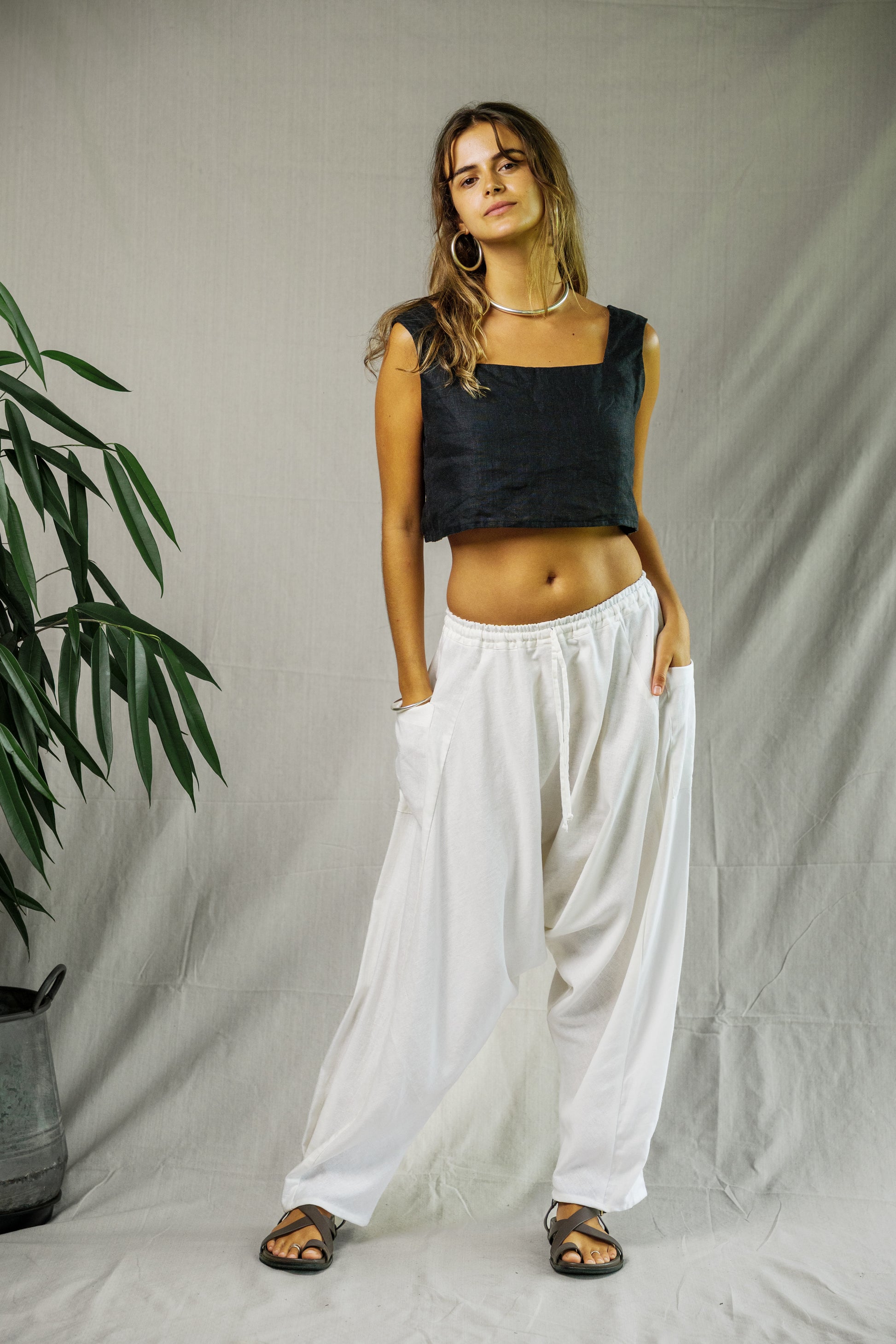 White linen wide-leg pants with pockets, paired with a black sleeveless square-neck top and black sandals.