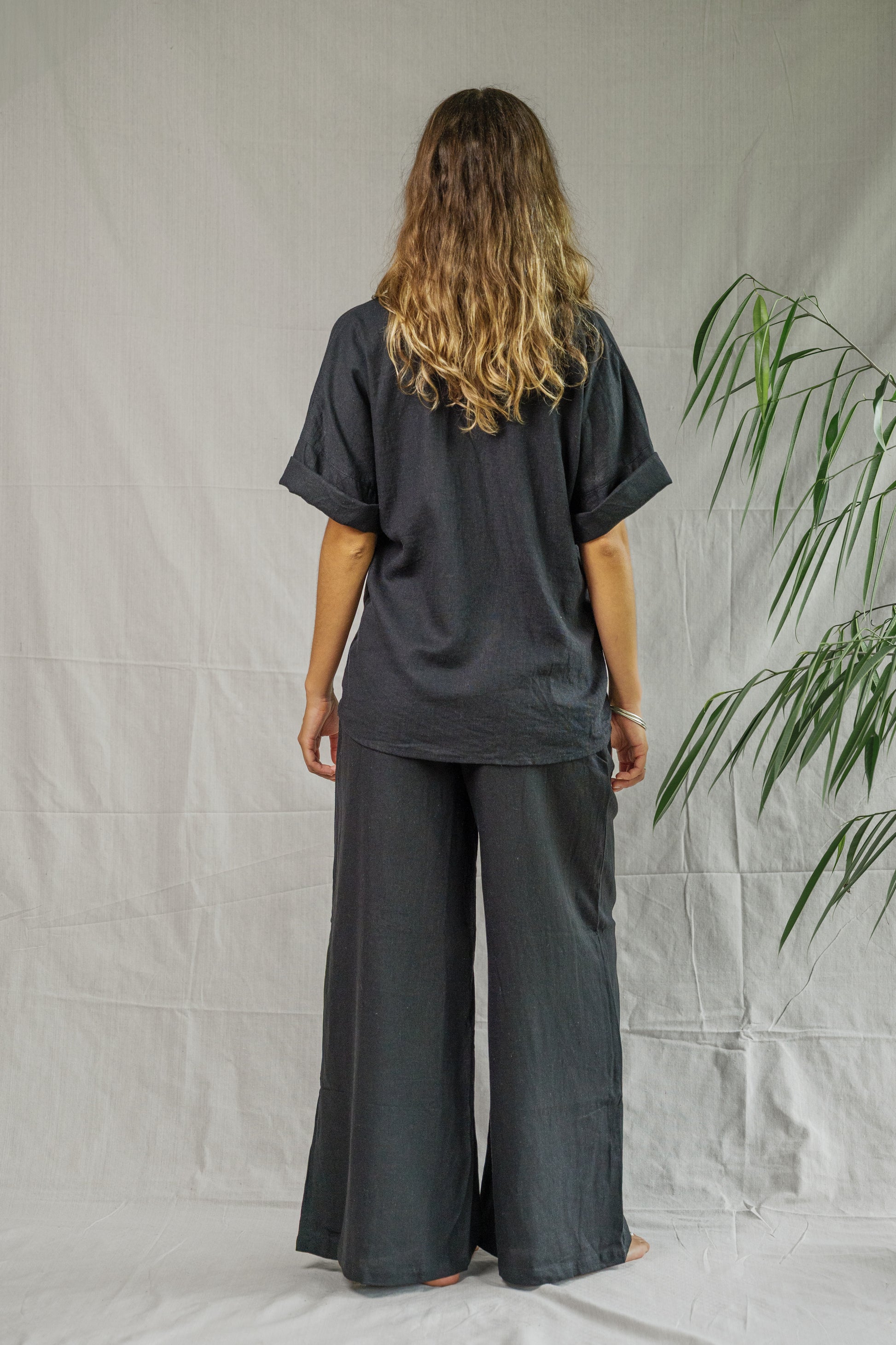 Black short-sleeve linen shirt with relaxed fit on model seen from back.
