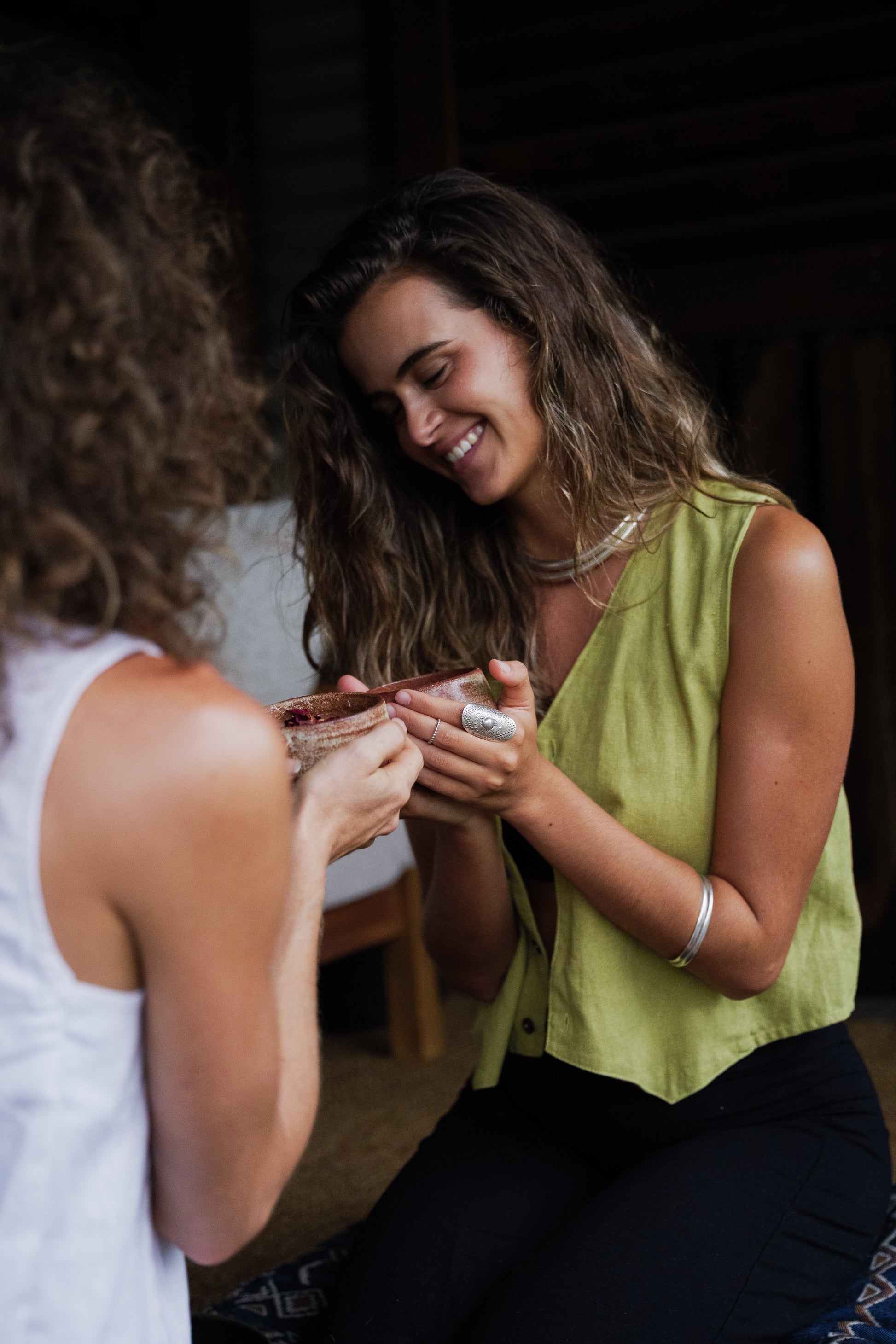 Sleeveless pistachio linen vest with a V-neck and relaxed fit worn by smiling woman.