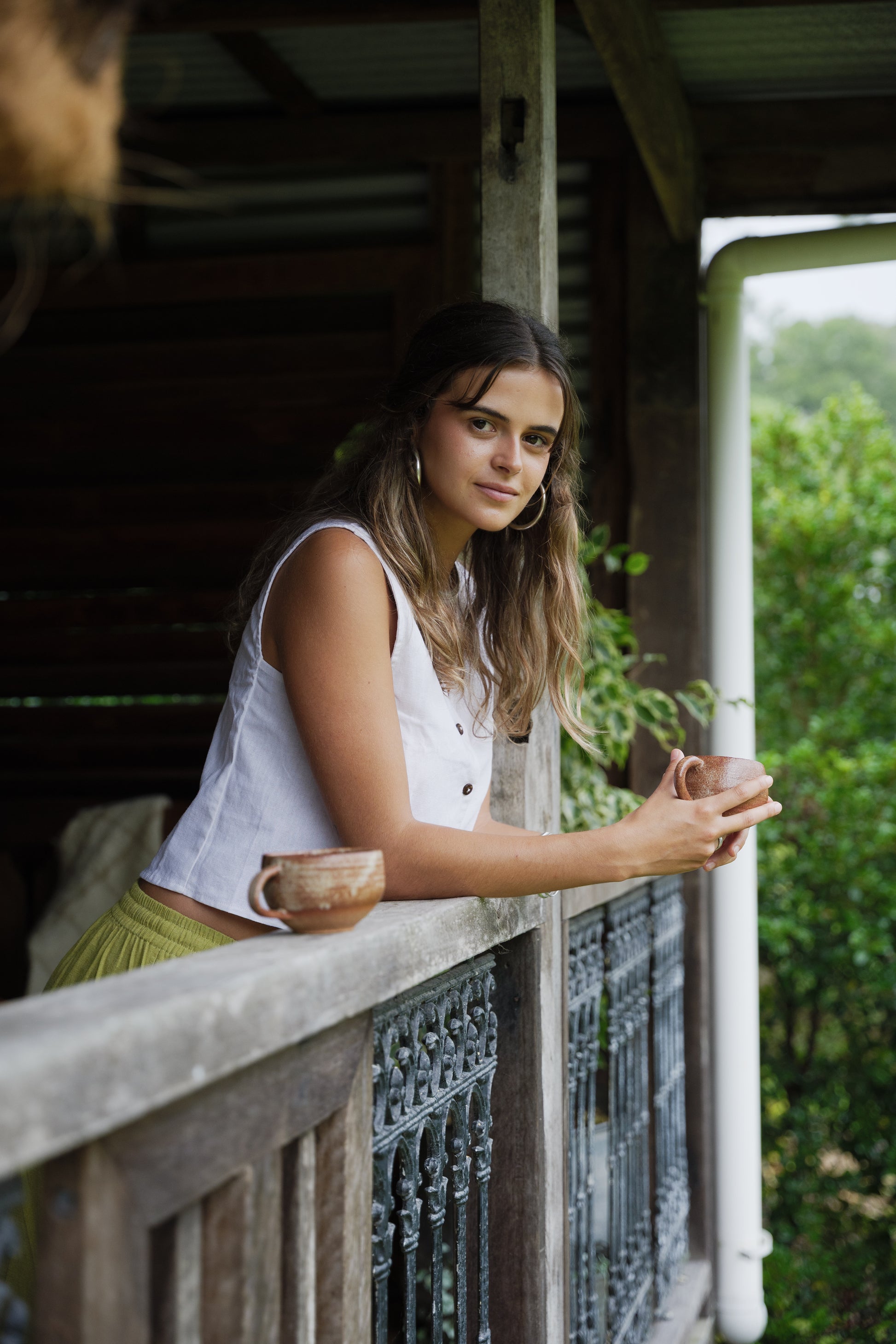Sleeveless white linen vest with buttons down the front, worn with yellow pants.