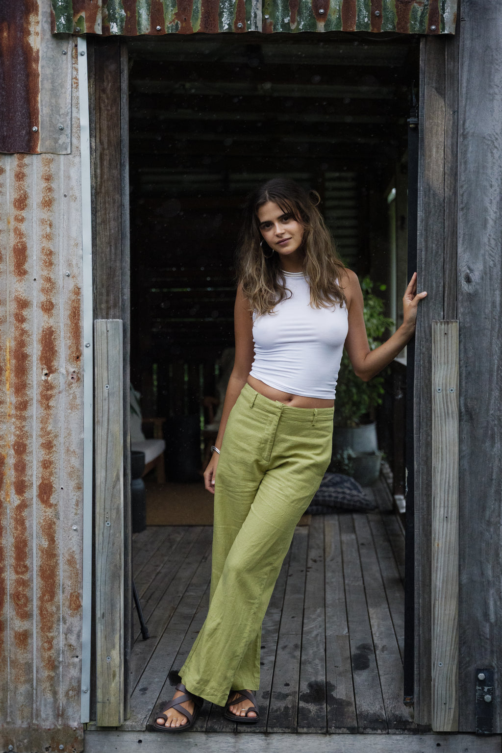 Light green linen wide-leg pants paired with a white sleeveless ribbed top and black sandals.