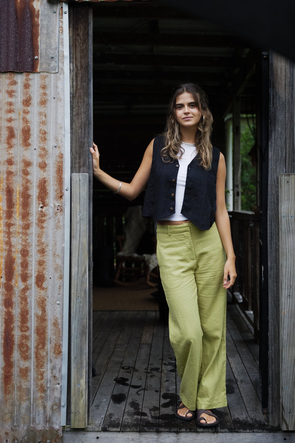 High-waisted pistachio linen pants with wide legs styled with a black sleeveless top and black sandals.