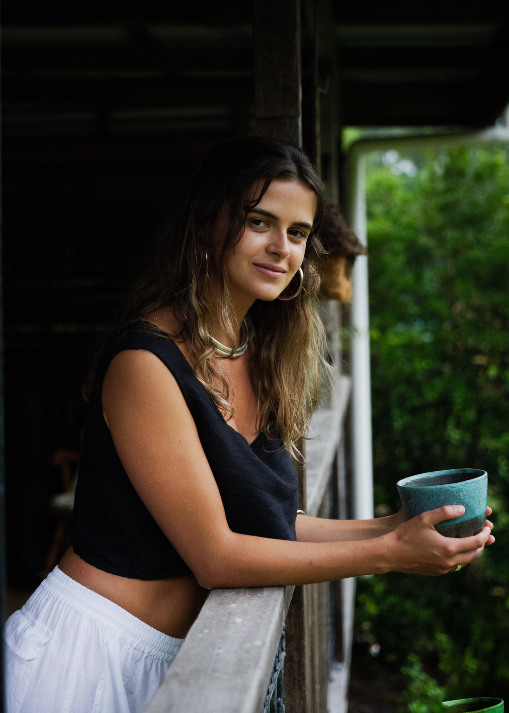 Black linen sleeveless crop top with deep V-neck worn with white pants.
