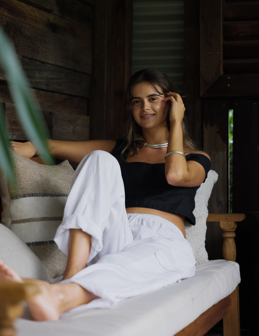 White linen cargo pants with relaxed fit and cuffed hems worn with black off-shoulder top.