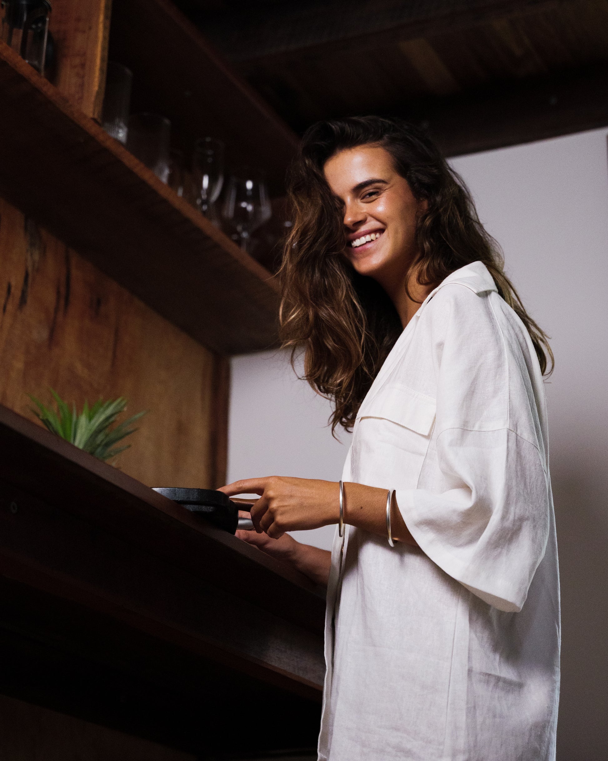 White linen loose-fit shirt with elbow-length sleeves and chest pocket, worn by smiling woman.